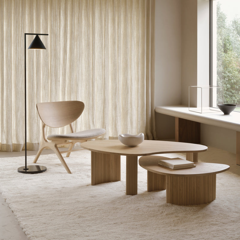 Boomerang Coffee Table in oak with modern design, paired with chair and floor lamp in minimalist living room.
