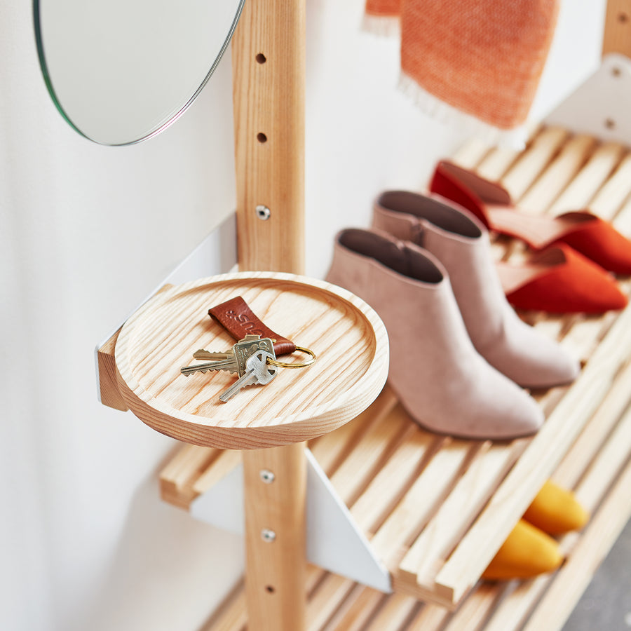 The Gus Modern Branch Side Tray holds keys on a wooden entryway organizer. Behind it, customizable open shelving stores boots and shoes, while an orange scarf hangs next to a round mirror.