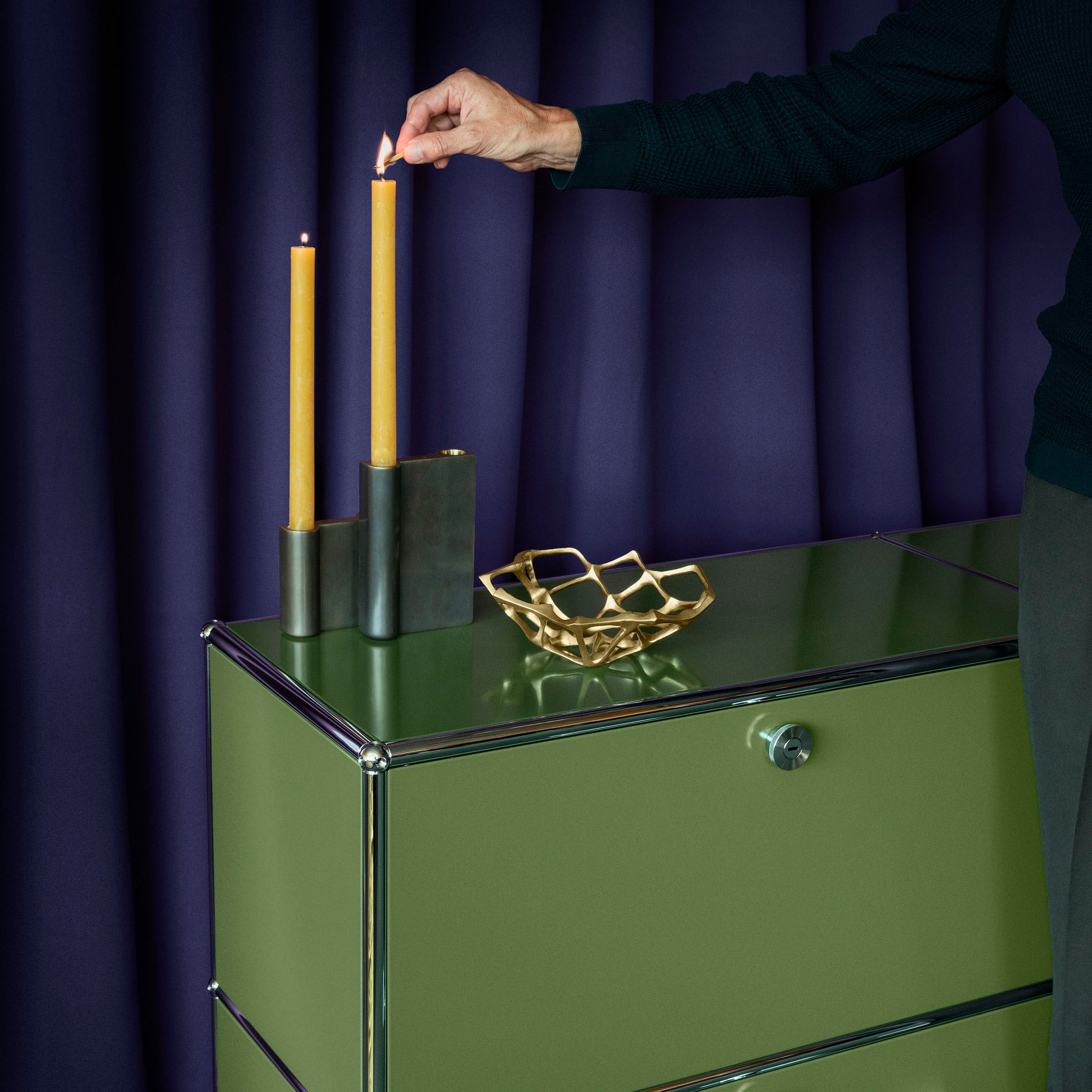 Green Haller Storage C1A18 credenza with chrome frame holding candles and a decorative bowl against a dark backdrop