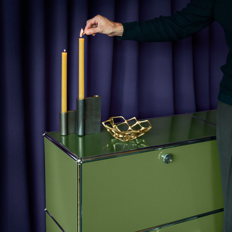 Green Haller Storage C1A18 credenza with chrome frame holding candles and a decorative bowl against a dark backdrop