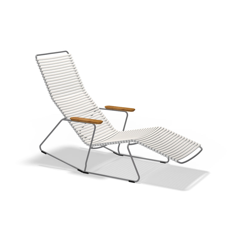 The Click Sunrocker by Houe is a modern lounge chair with a sleek design. It features a powder-coated steel tubular frame and white ribbed padding, complemented by wooden armrests and a slightly reclined backrest, creating a minimalist and comfortable aesthetic against a plain white background.