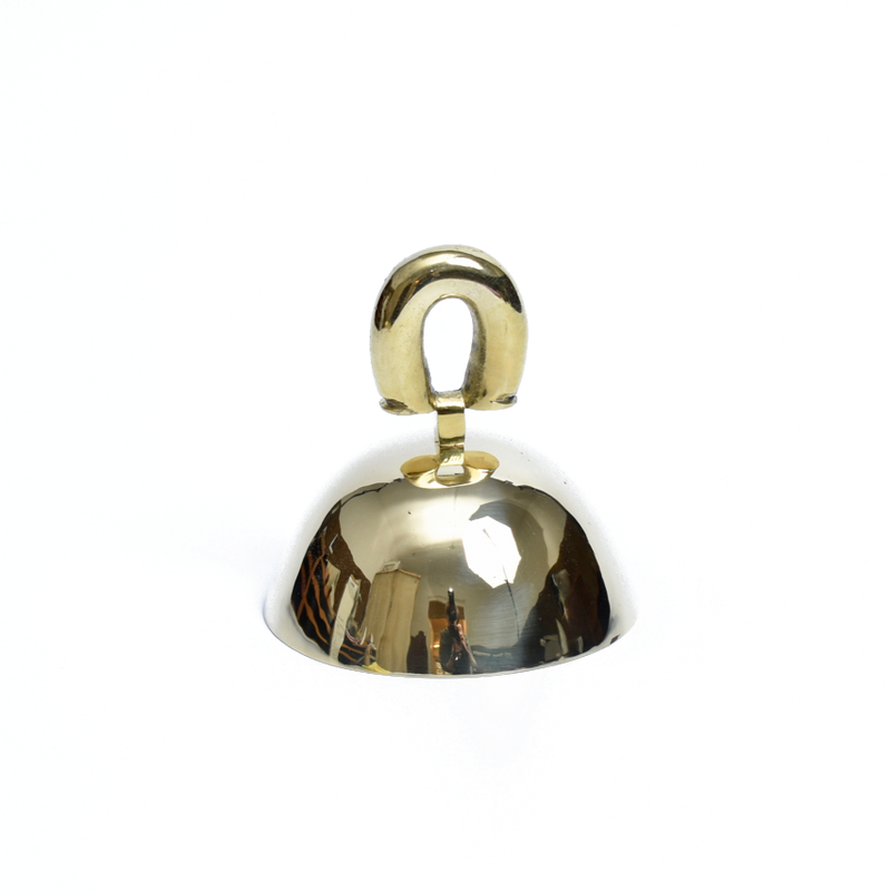 Bell #3310 by Werkstätte Carl Auböck is a shiny brass bell featuring a smooth, rounded body and an oval handle, evoking the elegance of a Viennese townhouse. Its polished surface reflects its surroundings beautifully.