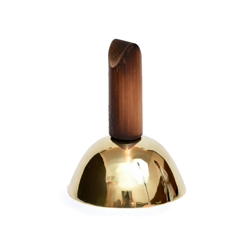 Bell #3310 by Werkstätte Carl Auböck features a shiny brass surface, reflecting light akin to sunlight on a Viennese townhouse, and stands upright with a smooth, rounded wooden handle against a white background.