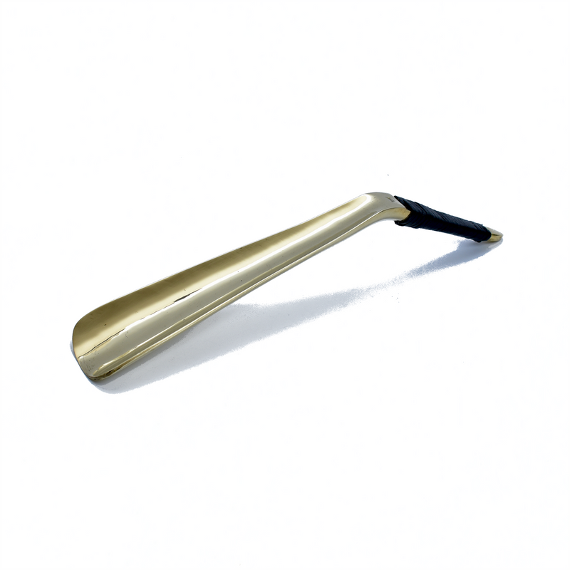 Shoehorn #4225 by Werkstätte Carl Auböck features a sleek metallic finish with a black handle, echoing Carl Auböcks minimalist designs, set against a plain white background.