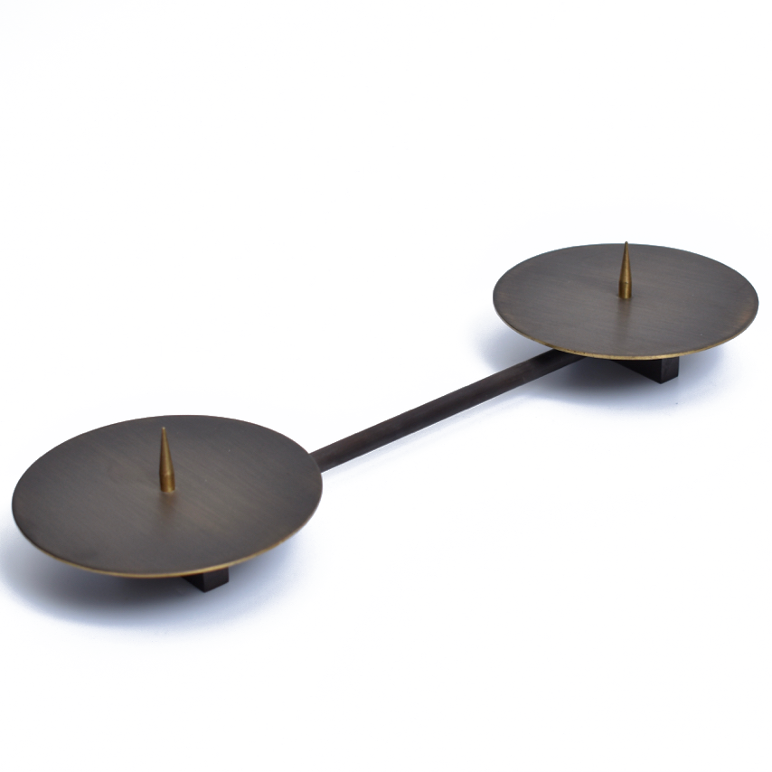 Candle Holder #4800 by Werkstätte Carl Auböck features two brass circular discs connected by a horizontal bar. Each disc, reminiscent of Wiener Bronzen style, has a pointed spike at its center against a plain white background.