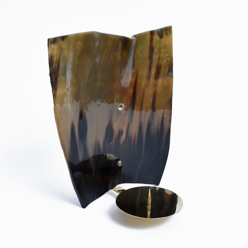 The Wall Candle Sconce #7257 by Werkstätte Carl Auböck features a tall, irregularly shaped brown and black surface with a glossy finish, positioned vertically on a white background, with a small round metallic disc attached near the bottom.