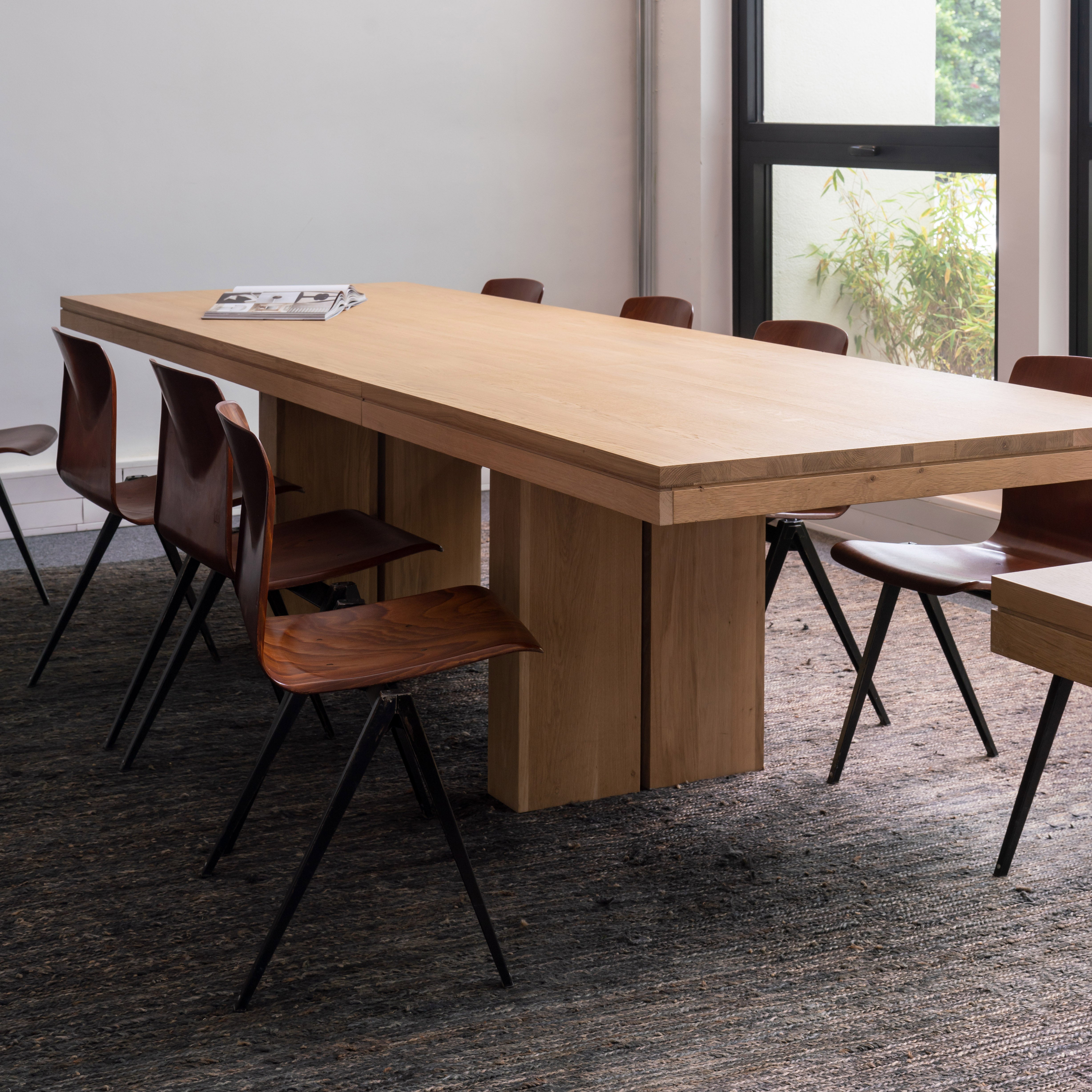 Double Extendable Dining Table in oak and teak with solid design and clean lines, set with modern wooden chairs in bright room.