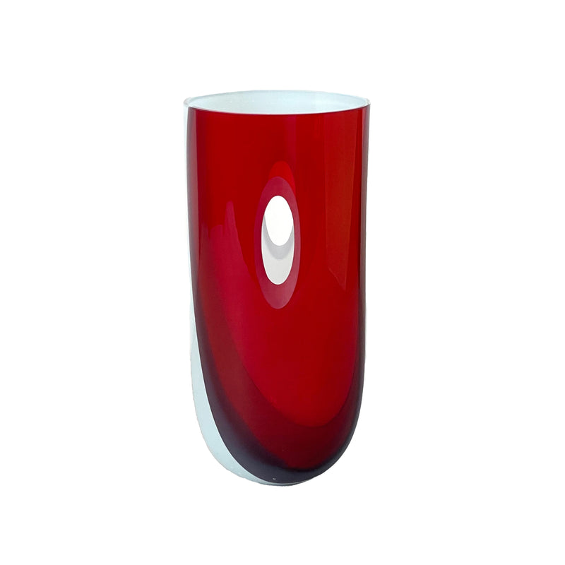 The ECLIPSE Vase by Ursula Futura is crafted from mouth-blown glass with a glossy red exterior and white interior. Its modern cylindrical shape features an elegant oval cut-out design and tapers slightly at the base for a sleek silhouette.