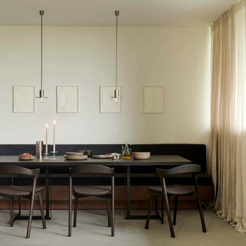 Bok Dining Chair - Upholstered in dark brown wood and leather around a modern dining table in a bright room