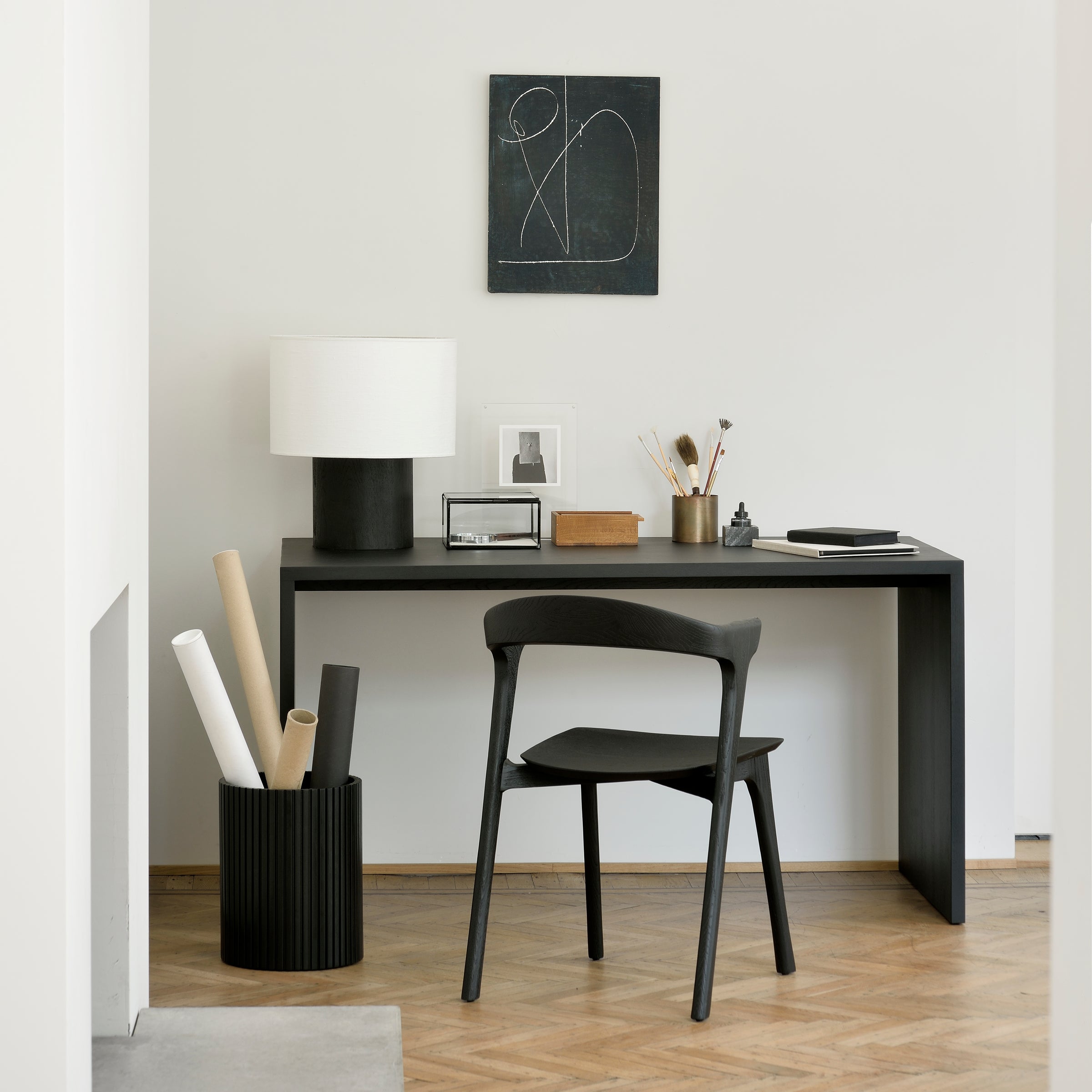 Bok Dining Chair in black varnished oak positioned in a minimalistic workspace with desk and lamp.