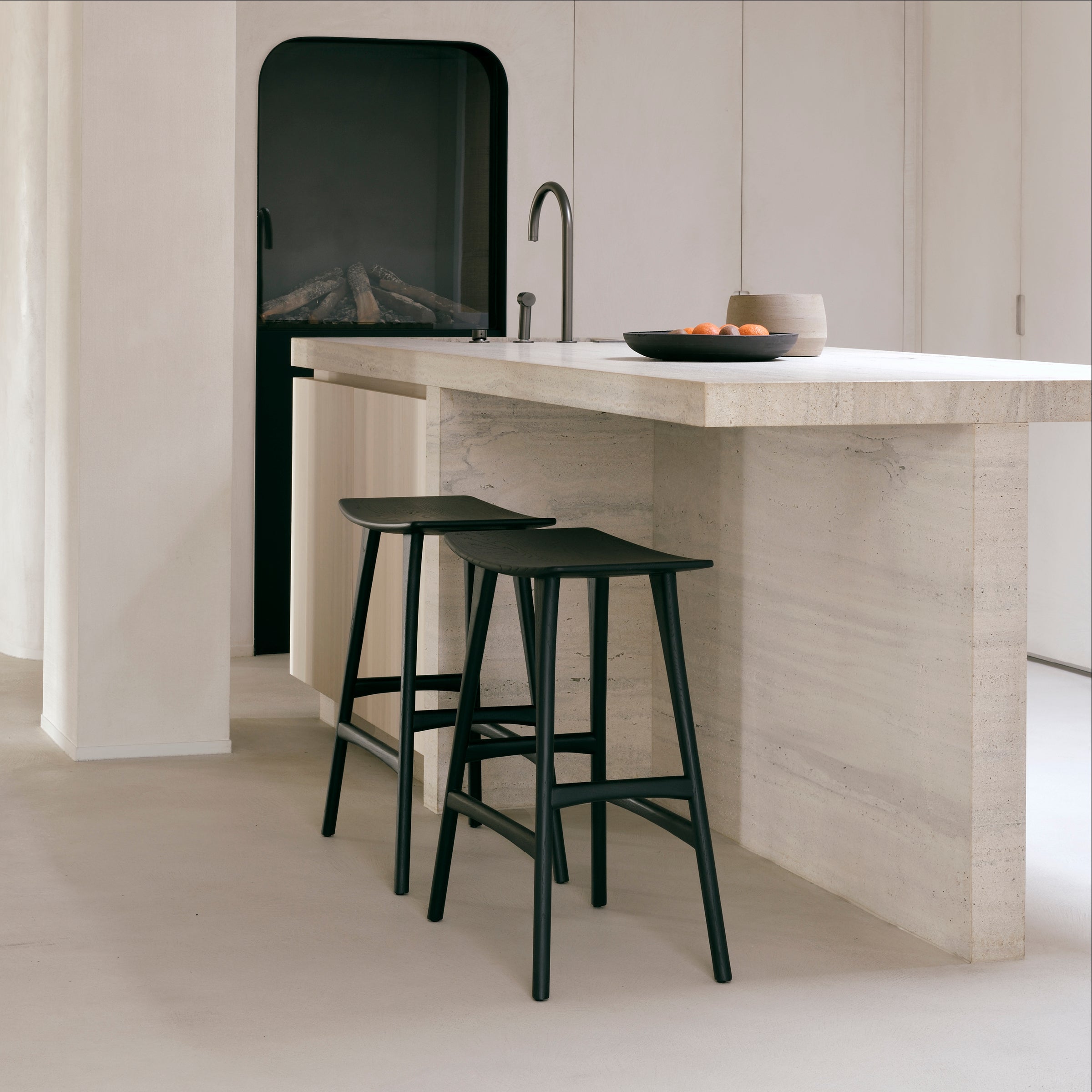 Osso Counter Stool in black varnished oak with sleek design, placed at a modern kitchen island.