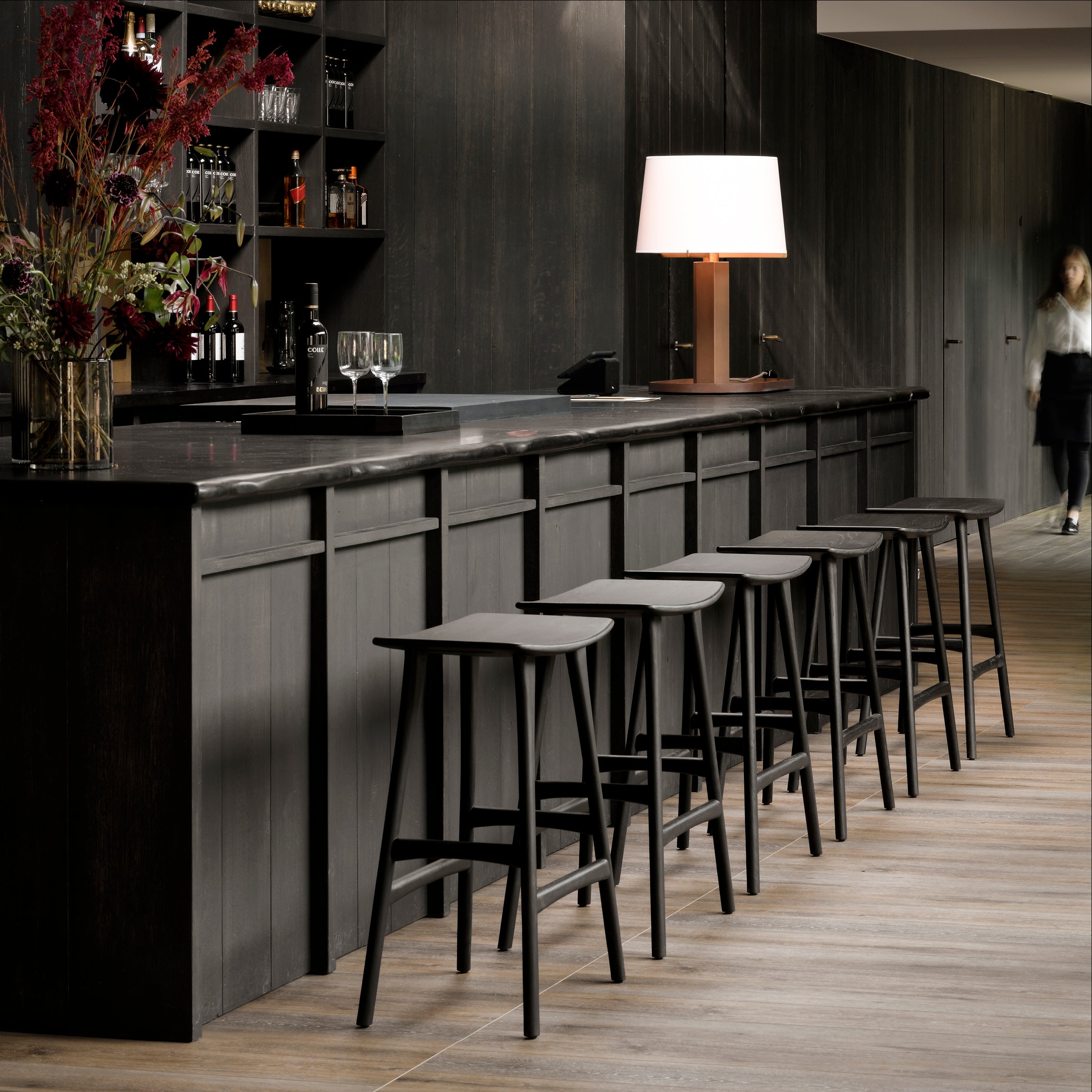Osso Counter Stool set in black varnished oak with sleek design arranged along a modern kitchen bar.