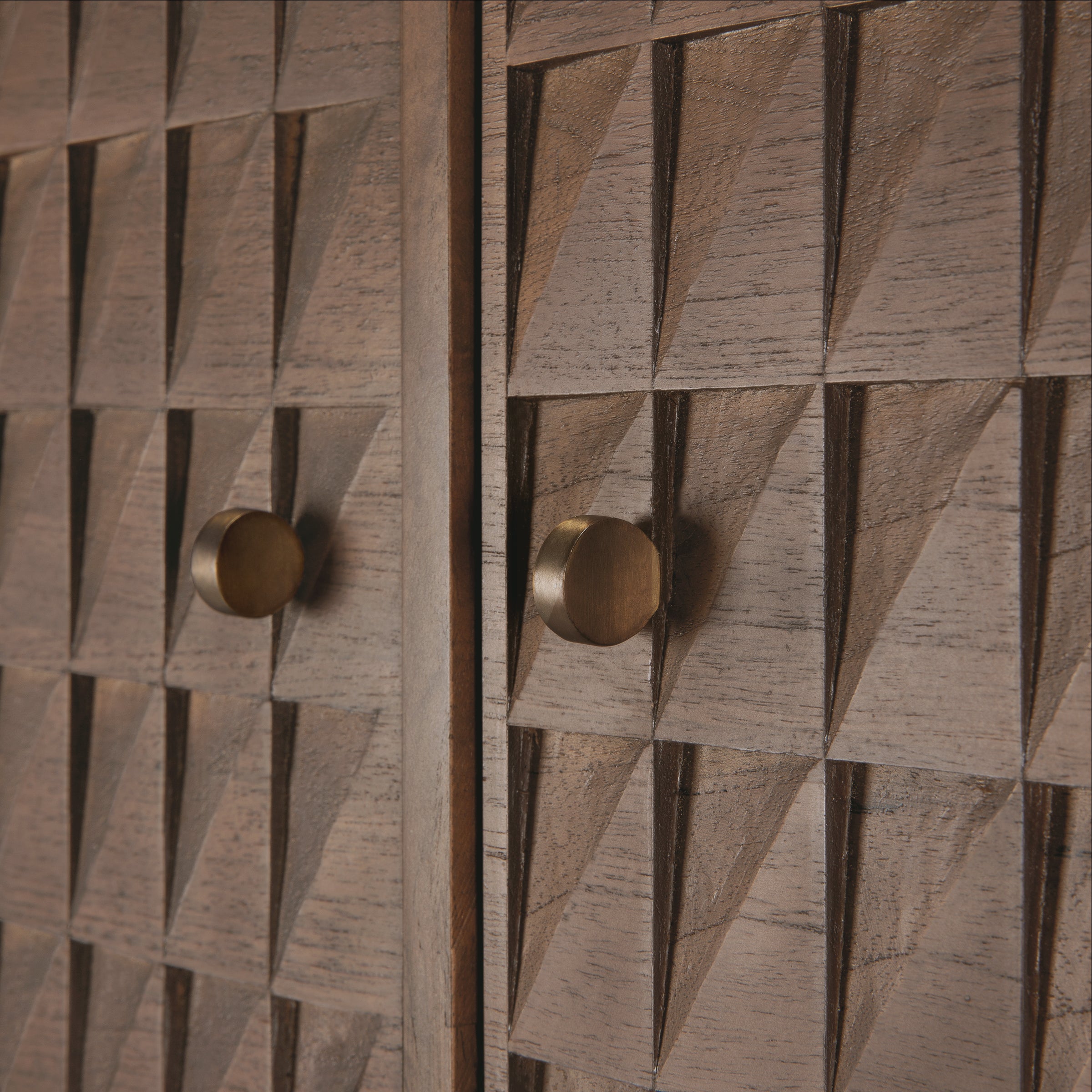 Close-up of hand-carved teak wood panels with brass handles on the Sono Cupboard by Ethnicraft.
