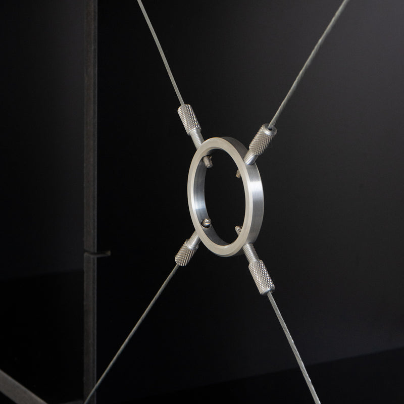 On a dark background, the FNP by Moormann showcases an adjustable design with a metal ring suspended by four cables arranged in an X shape, screwed into place.