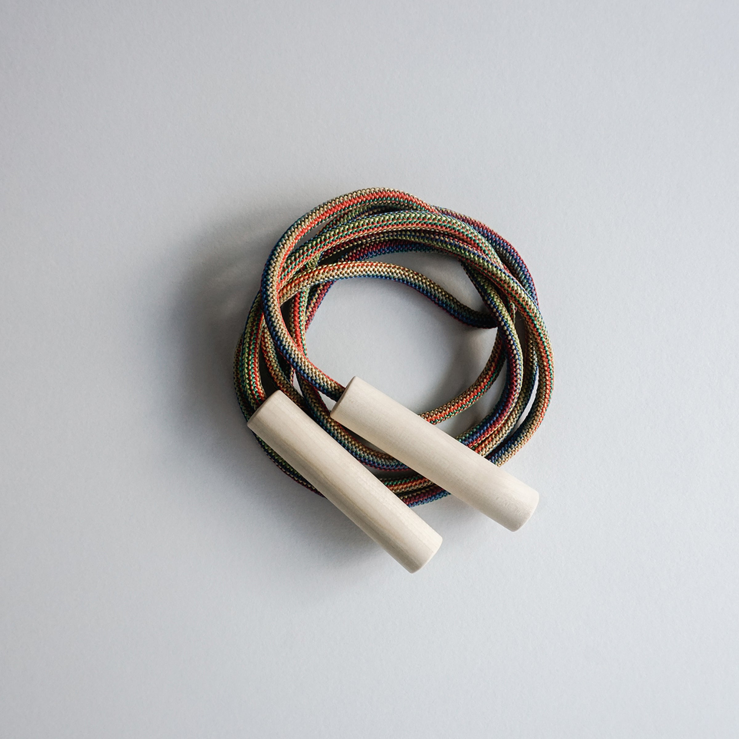 Check out the vibrant Spring skipping rope by GoodGoods, expertly coiled on a light surface. Featuring ash wood handles and a multicolored design along its 86.6 length, this woven jump rope is ideal for kids who want fun and fitness.