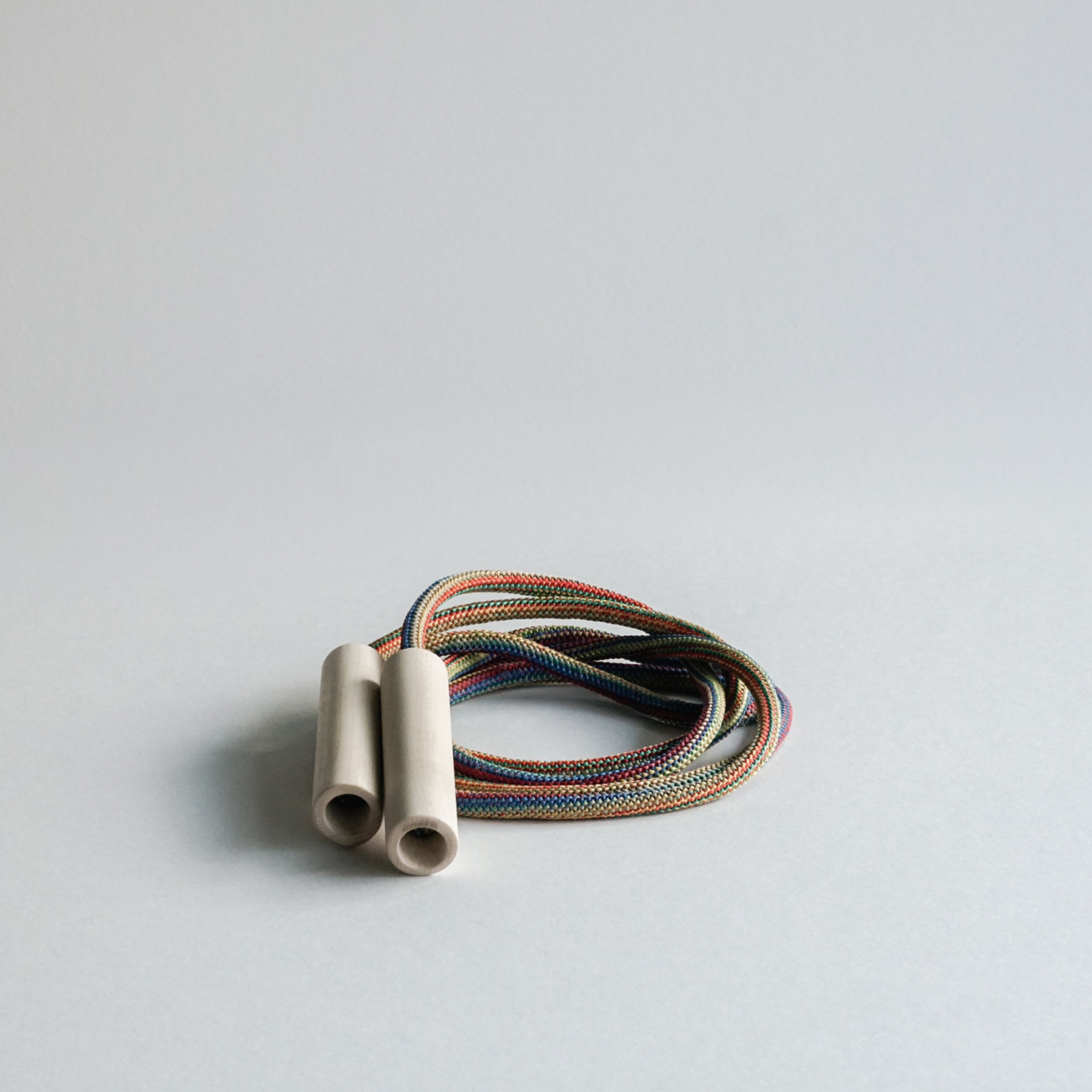 The GoodGoods Spring skipping rope, designed for kids at 86.6, is coiled on a light gray surface. Its vibrant colors contrast with plain white handles, highlighting quality materials ideal for energetic play.