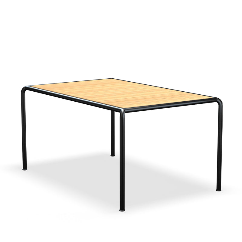The Avanti Table by Houe features a smooth rectangular wooden top and slim black metal legs, embodying modern elegance. Its modular design provides versatility, and the minimalistic flooring beneath enhances its sleek appearance.
