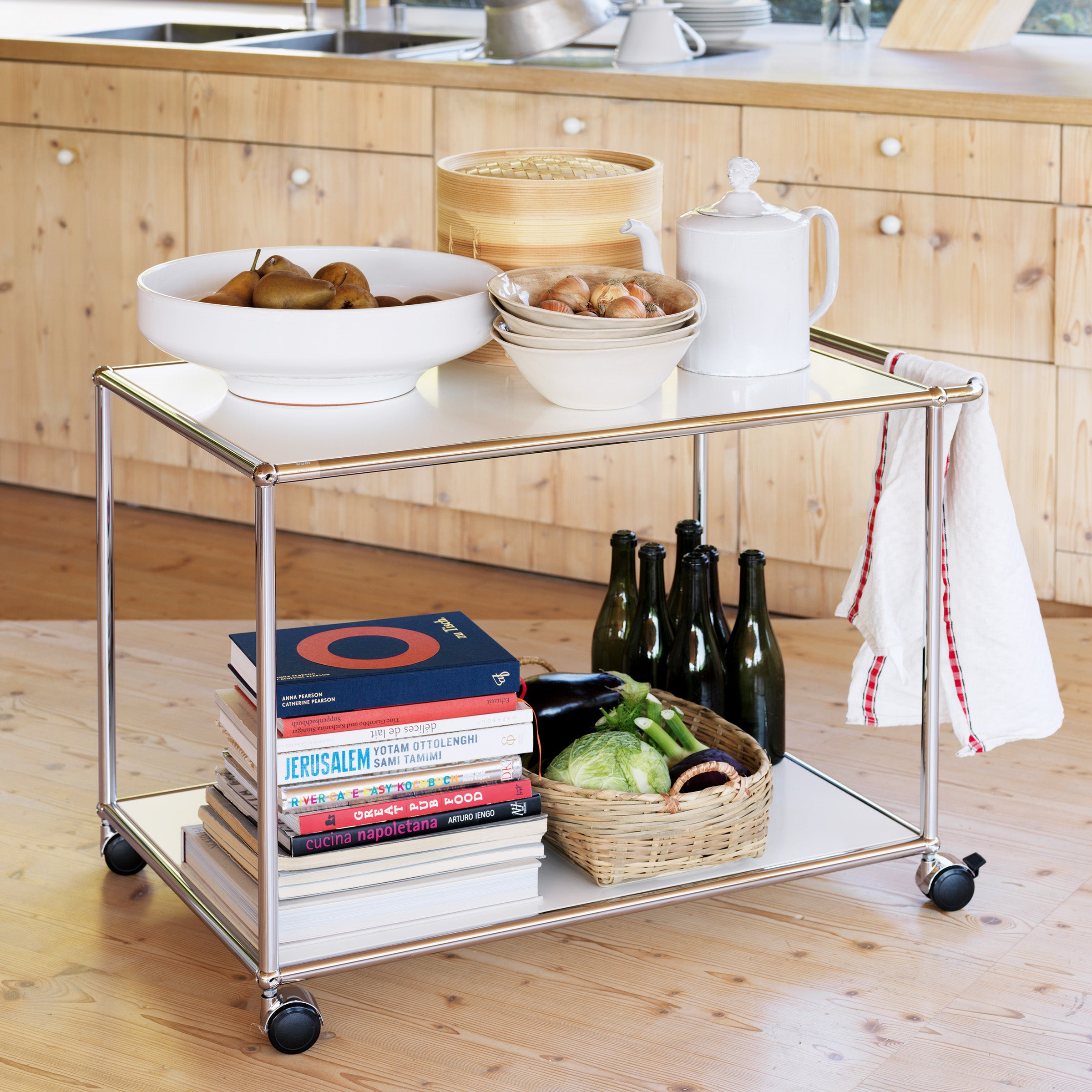 Haller Serving Cart L18 with chrome steel frame and powder-coated panels, shown with kitchen items and books.