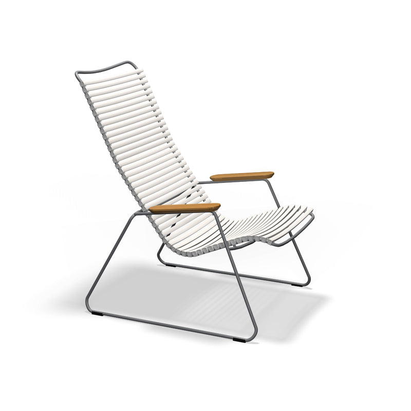 The Click Lounge Chair by Houe boasts a minimalist design with a weather-resistant white slatted seat and backrest on a sleek metal frame, equipped with wooden armrests and slightly reclined angles for comfort, perfect for stylish outdoor settings.