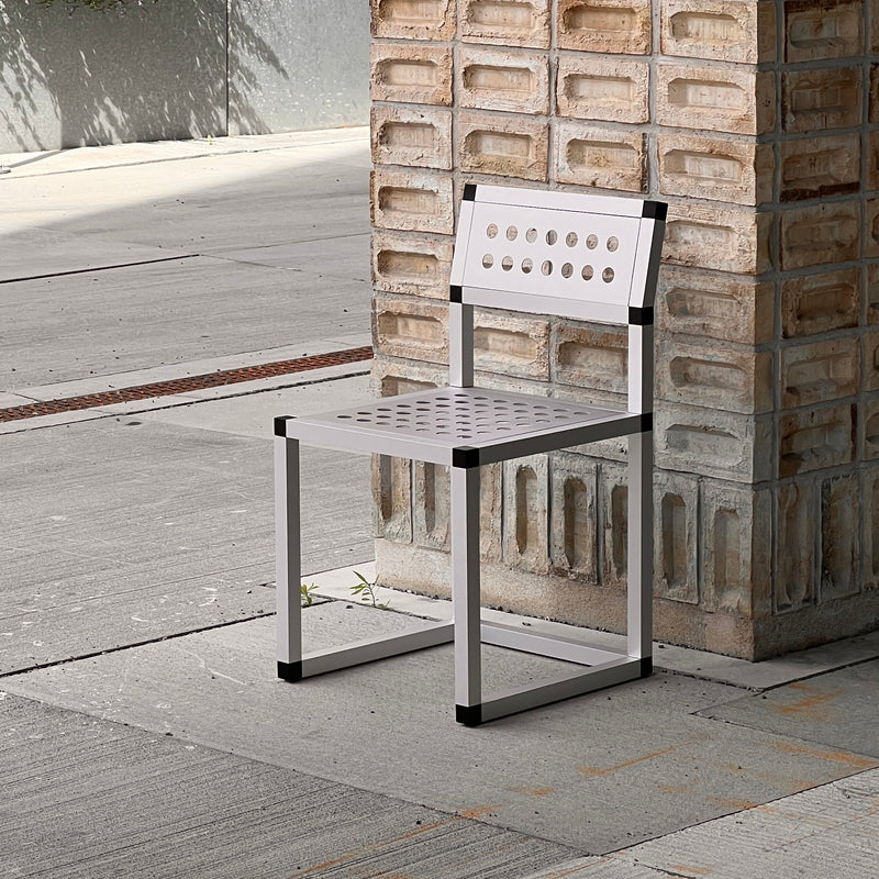 Modern metal chair against a textured stone wall with outdoor setting