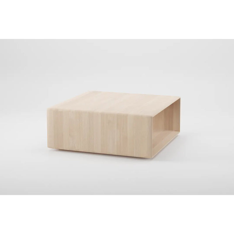 The INVITO Cube Coffee Table by Artisan is a square, solid wood piece with a light, natural finish. It features a minimalist design with clean lines and an open shelf beneath the tabletop. Made from environmentally-friendly materials, it stands out against a plain white background.
