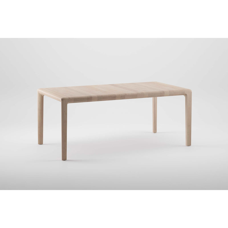 The INVITO Table by Artisan is a minimalist piece made from solid, light-colored wood with a natural oil finish. It features a smooth surface and four slender legs, set against a plain white background.