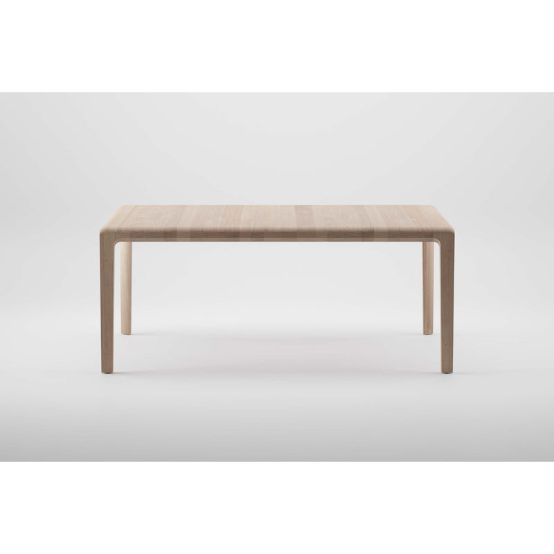 The INVITO Table by Artisan is a minimalist piece crafted from solid wood with a light grain finish. Featuring a rectangular top and four straight legs, it highlights the use of eco-friendly materials against a plain white background.