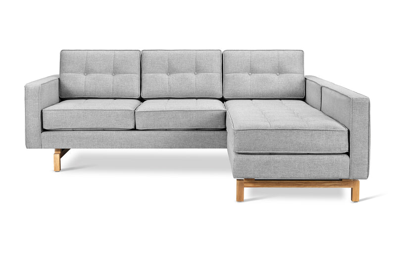 The Jane 2 LOFT Bi-Sectional by Gus Modern features a modern light gray design with tufted cushions, square arms, wooden legs in a natural finish, and a right-facing chaise for a refined mid-century look.