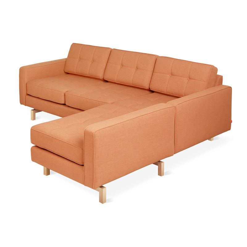An orange Jane 2 LOFT Bi-Sectional with tufted cushions and a natural finish base by Gus Modern, mid-century inspired with an L-shape and wooden legs, is shown against a white background.