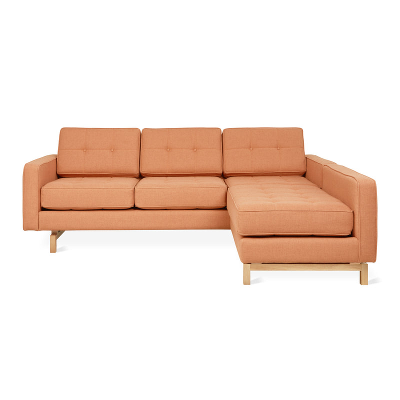 The Jane 2 LOFT Bi-Sectional by Gus Modern features vibrant orange upholstery, a natural finish base, three seat and back cushions, and a right-side chaise lounge, all inspired by mid-century design.