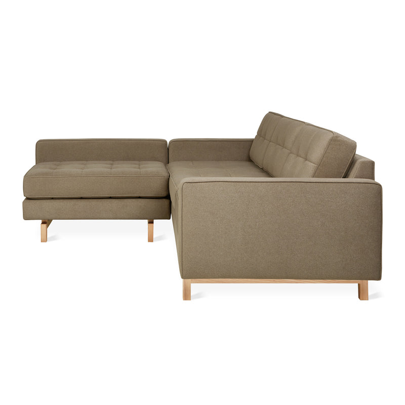The Gus Modern Jane 2 LOFT Bi-Sectional in brown features mid-century design, a left-facing chaise, tufted cushions, low wooden legs with a natural finish base, and clean lines—seen from an angle highlighting the chaise.