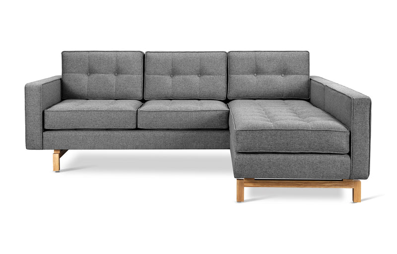 The Gus Modern Jane 2 LOFT Bi-Sectional Natural Finish Base is a modern gray sectional with tufted cushions, three seat backs, a right-facing chaise, square arms, and light wooden legs for an elegant mid-century look.