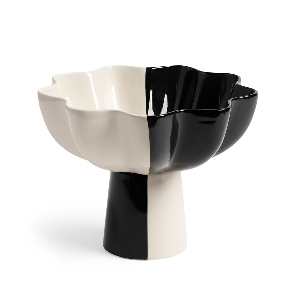The Fruit Bowl Sun Black Large by &Klevering features a wavy edge and a pedestal base, divided into black and white. Its glossy surface enhances its symmetrical design, with subtle multicolor hints adding whimsy.