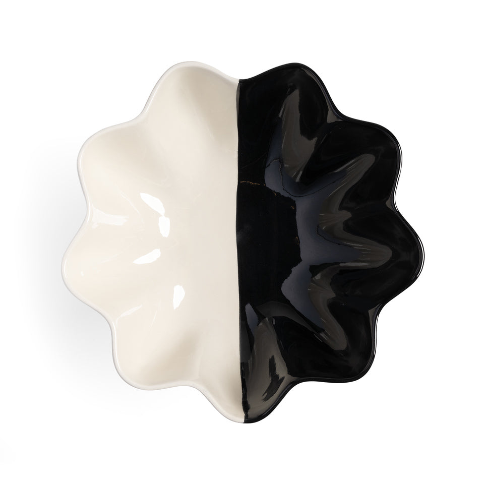 The &Klevering Fruit Bowl Sun Black Large features a wavy, scalloped-edge design divided into two equal halves: glossy white on the left and glossy black on the right. This creates a striking multicolor contrast viewed from above, highlighting its elegant symmetrical design.