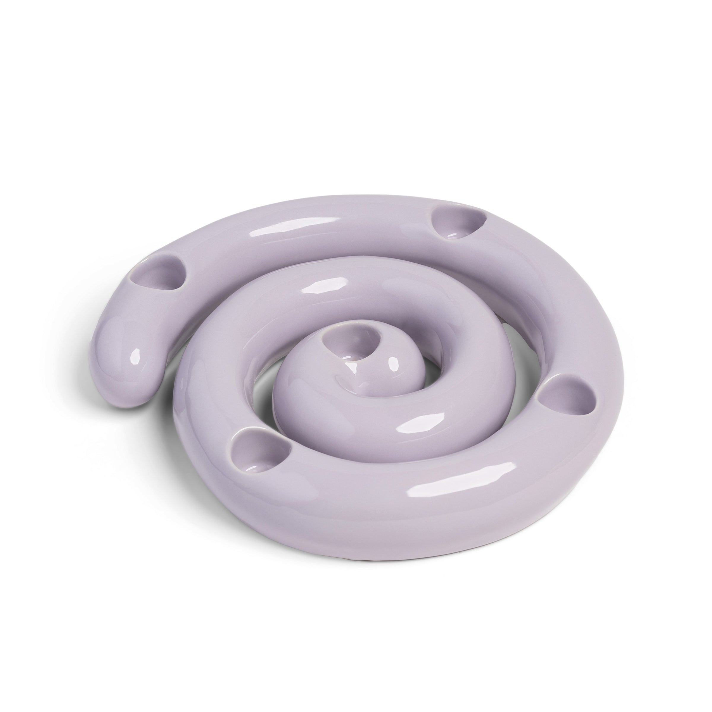 The Candle Holder Scribble by &Klevering is a glossy, lavender ceramic piece spiraling inward like a coiled snake. It resembles a porcelain candle holder with smooth, reflective curves and several evenly spaced small holes.