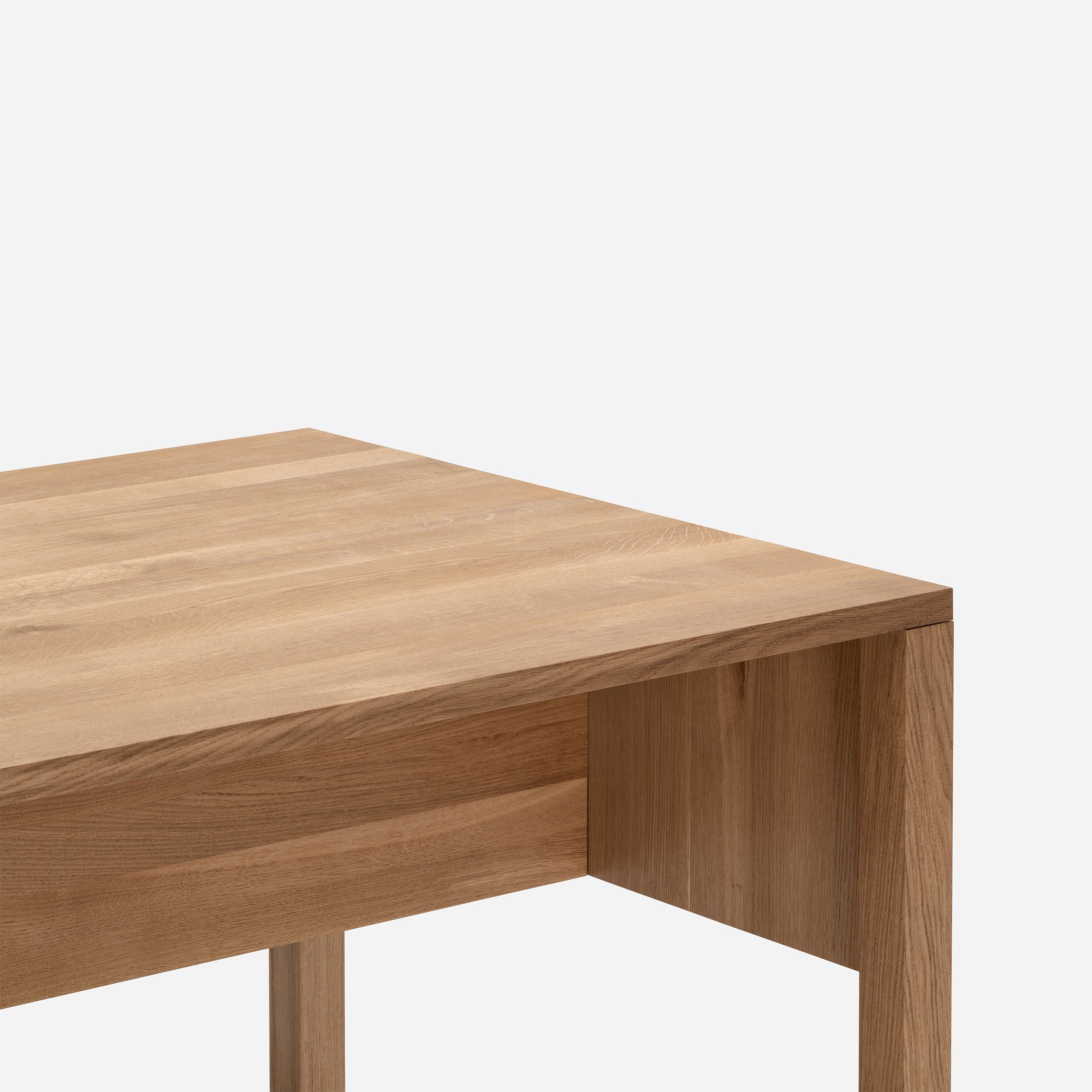 The L8 Traba Table by Loehr is displayed in close-up, showcasing its solid wood construction with a smooth, light brown finish against a white background. Its simple, modern design exemplifies elegance and structural rigidity.