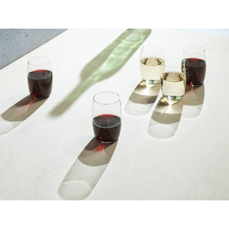 Five Wiener Achtel stemless wine glasses by Lobmeyr rest on a light surface with elongated shadows. Two hold white wine and three red, creating striking contrasts that evoke modern design and the elegance of Lobmeyr craftsmanship.