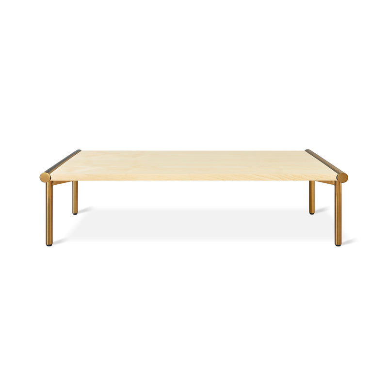 The Manifold Coffee Table Rectangle by Gus Modern features a light wood top and four slim gold-colored metal legs. This modern rectangular coffee table is shown against a white background.