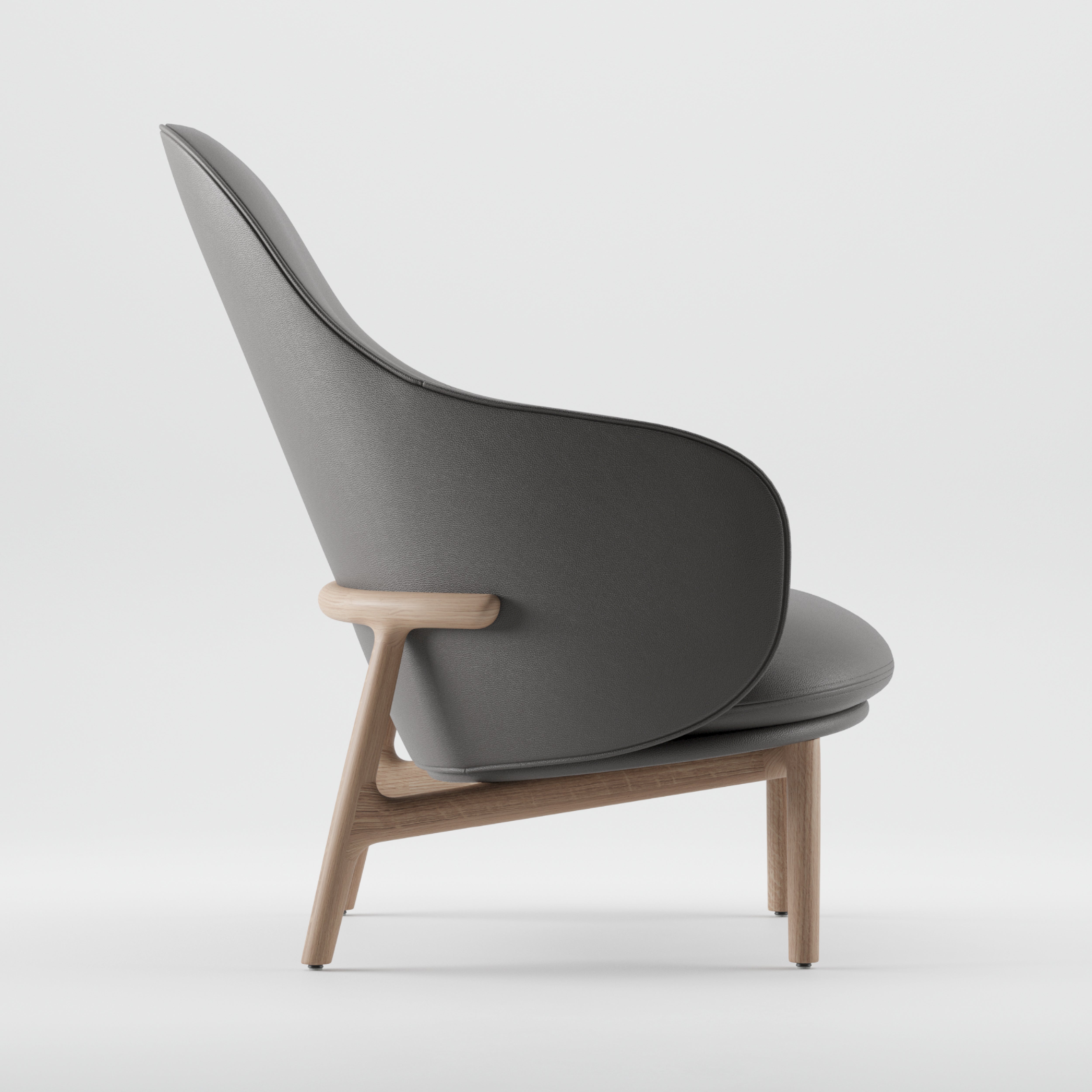 Side view of the Artisan MELA Lounge Chair High, featuring a mid-century inspired, minimalist design with gray upholstery on the seat and backrest. It has smooth curves, a light wooden frame, armrests, and a slightly reclined back.