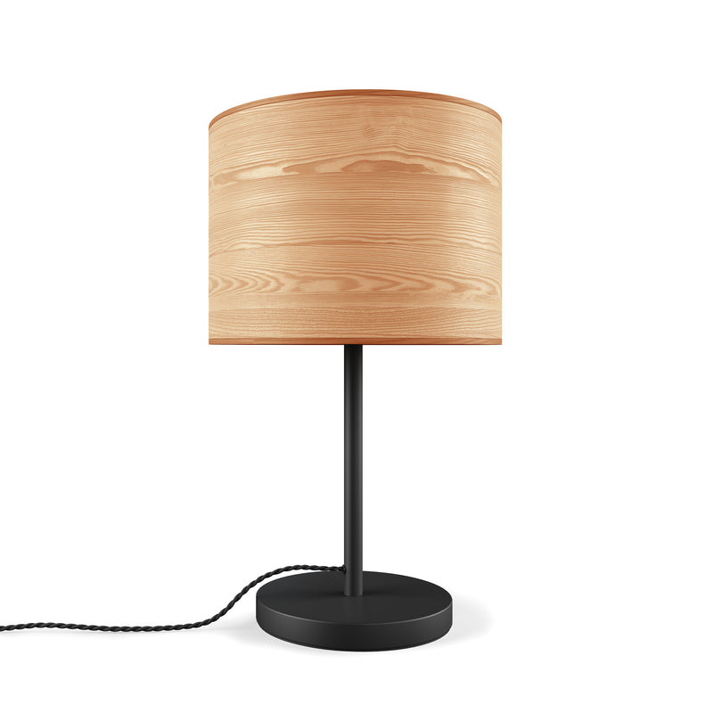 The Milton Table Lamp by Gus Modern has a light wood cylindrical shade, slender black metal stand, round black base, and twisted black cord—a modern rustic accent against a white background.