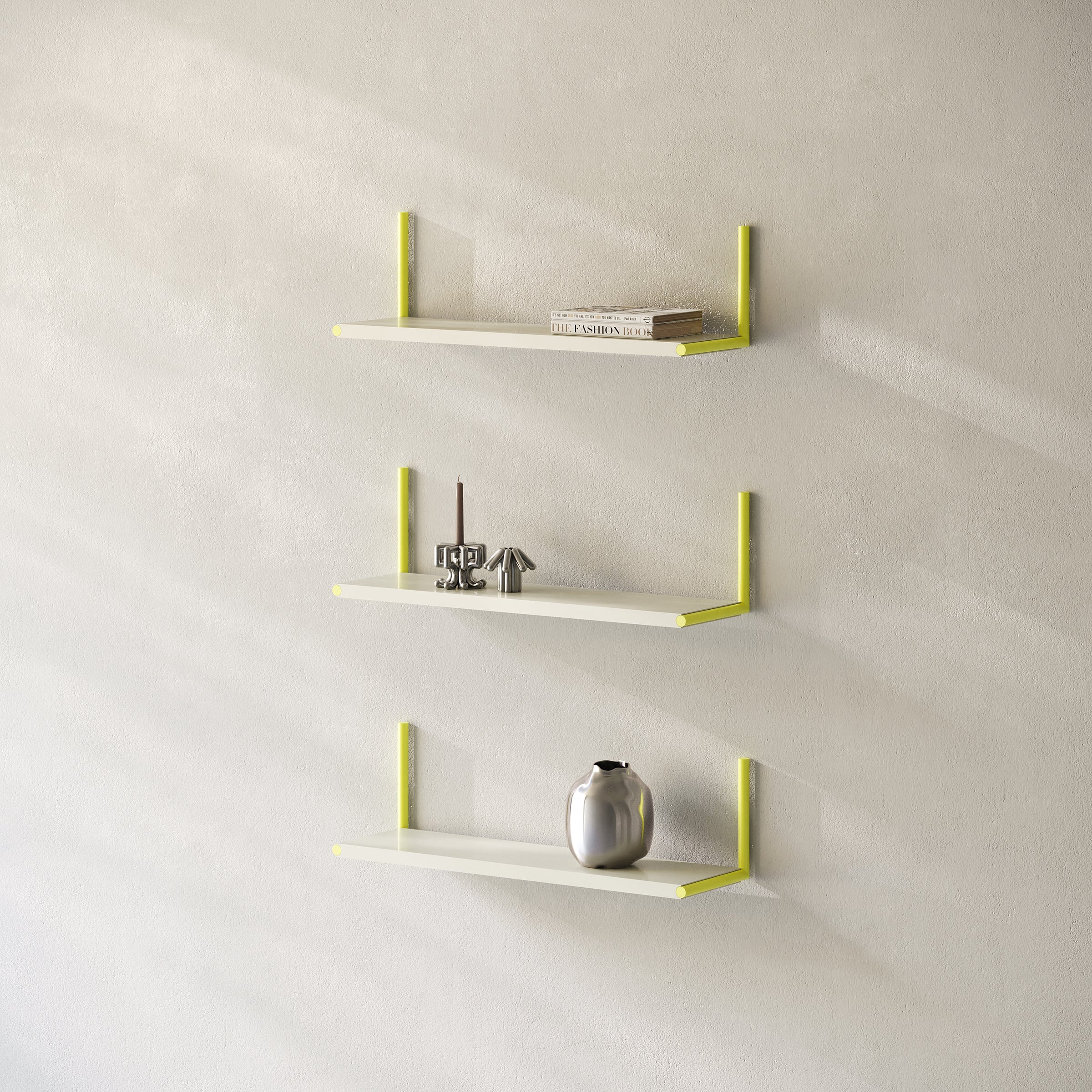 Three ELLE Shelf units mounted vertically with yellow brackets holding decor and books on a light wall.