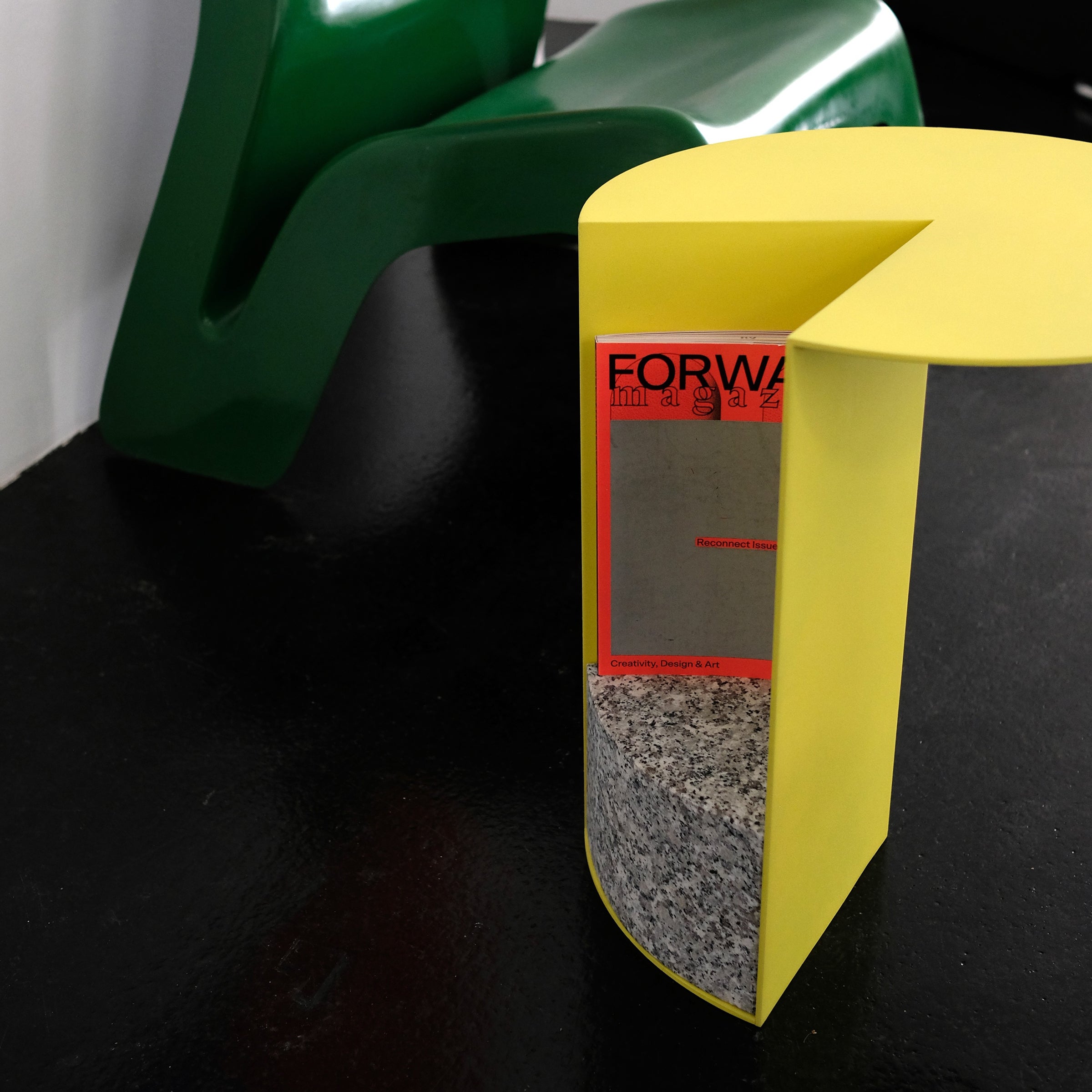 PAC 450 Side Table in sulfur yellow with granite base and powder-coated aluminum tabletop holding a magazine.