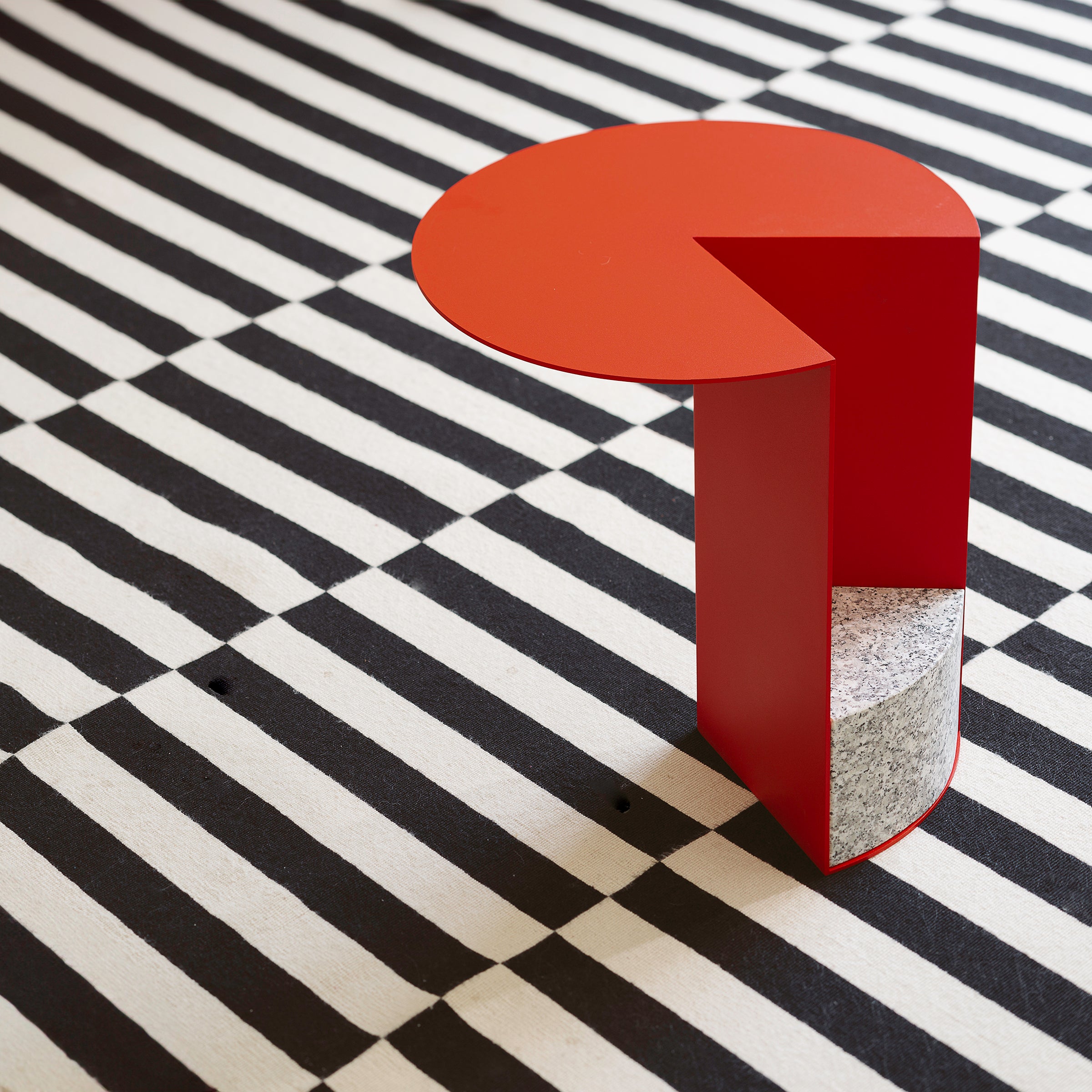 PAC 450 Side Table in traffic red with granite and powder coated aluminum on black and white striped floor.