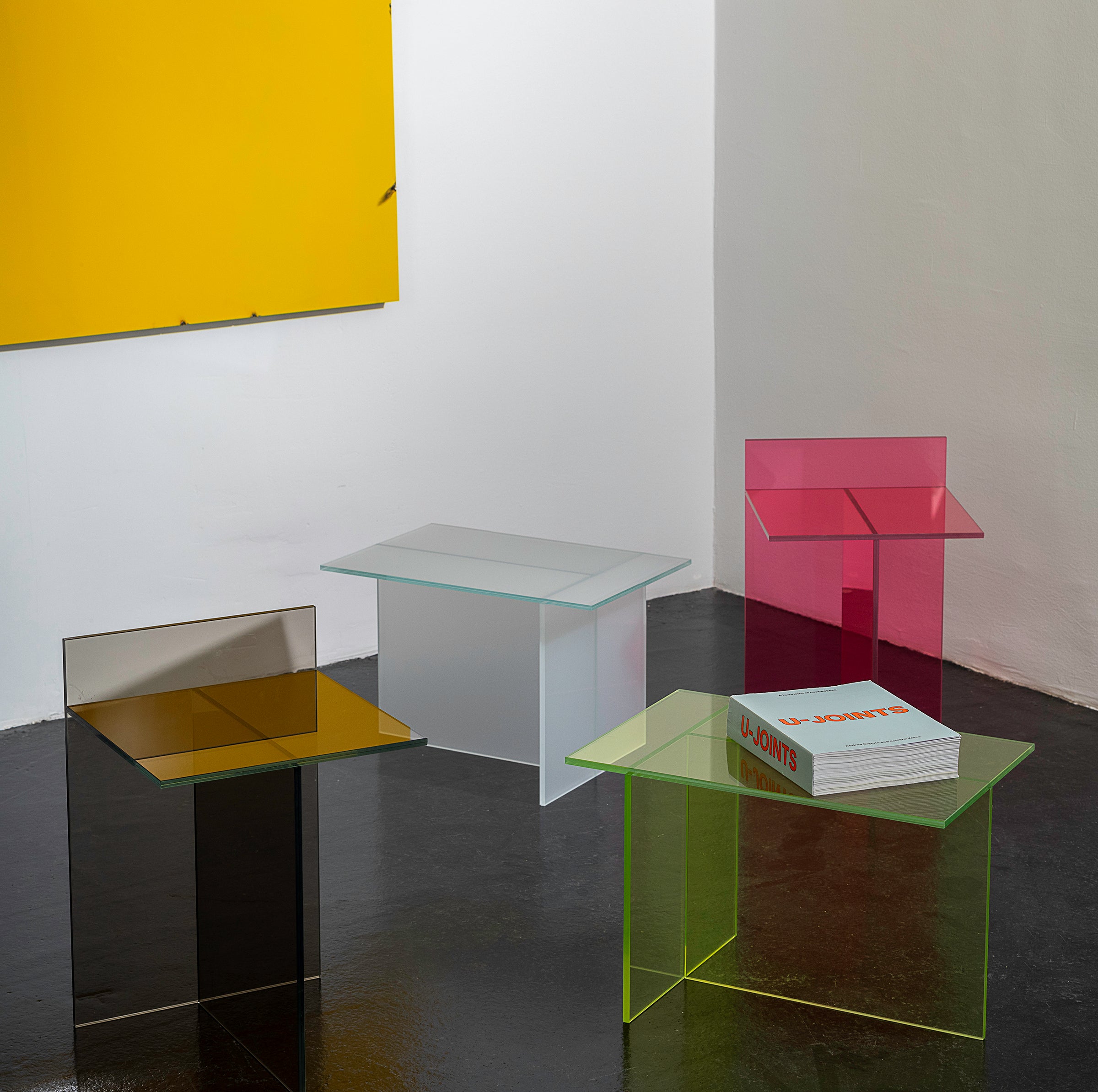 THEO Glass Side Table in various colors showcasing intersecting glass elements forming a T shape, modern and versatile design.