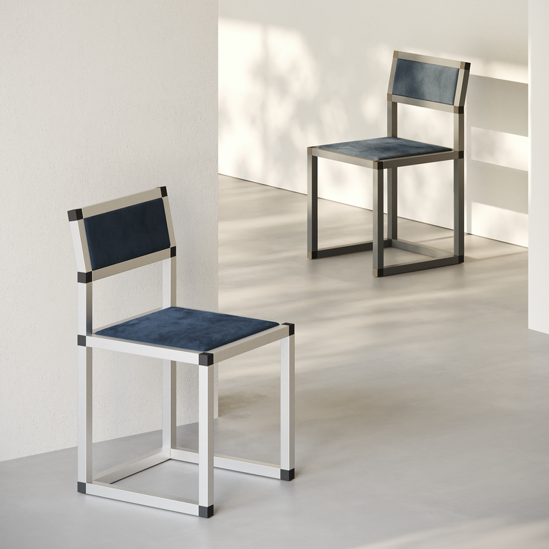 Two XD Chairs with aluminum frames and dark blue upholstery displayed in a minimalistic room setting.
