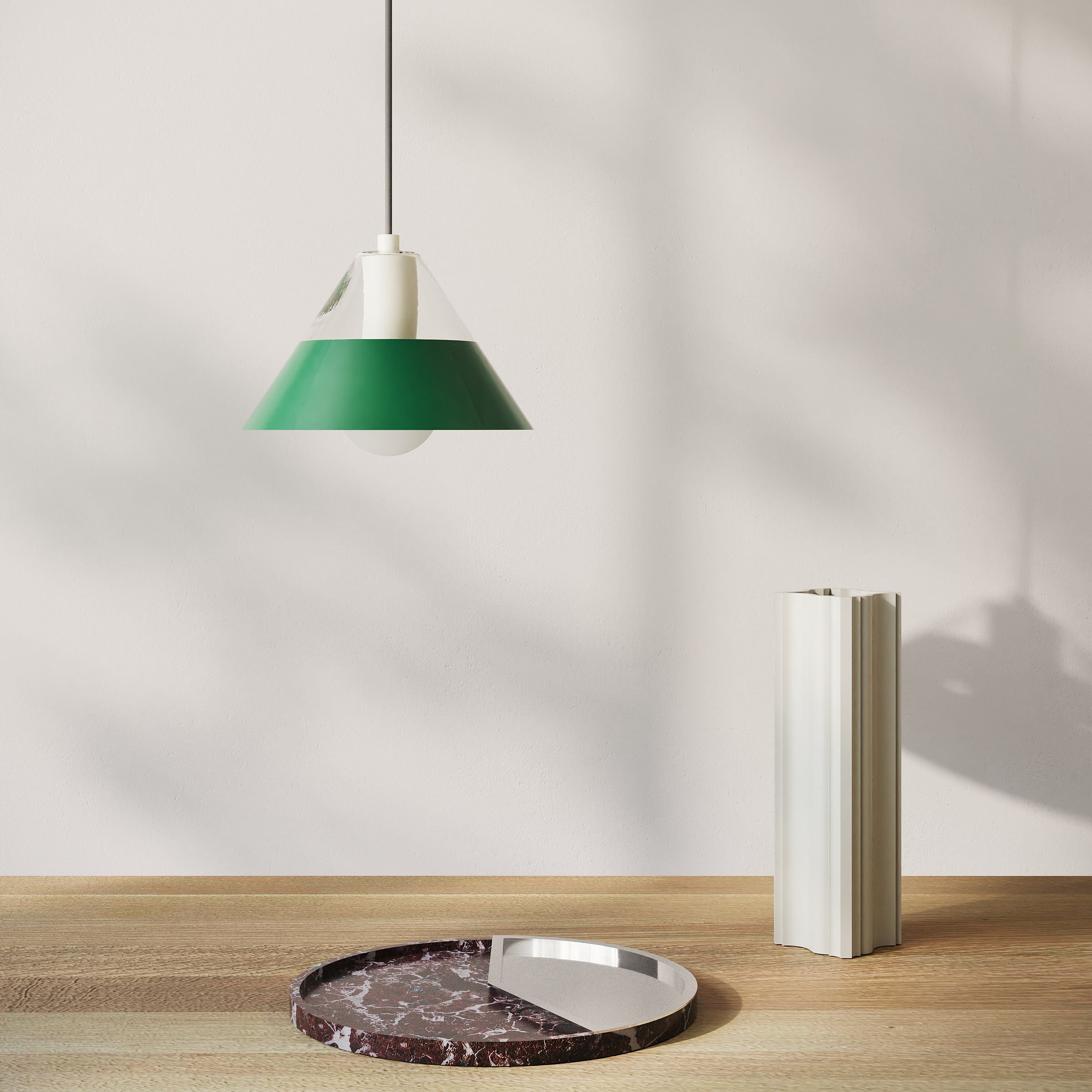 FIFTY FIFTY lamp with green metal shade and glass top hanging above a wooden table with decorative objects.