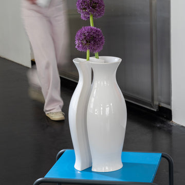 QUATER Vase III white glossy matte ceramic vase with purple flowers on a blue table in a modern interior.