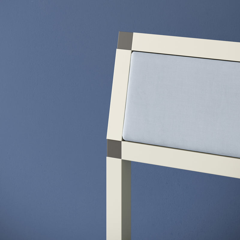 Close-up of cleanroom white matte aluminum frame and light blue upholstery on the XD Chair against blue background