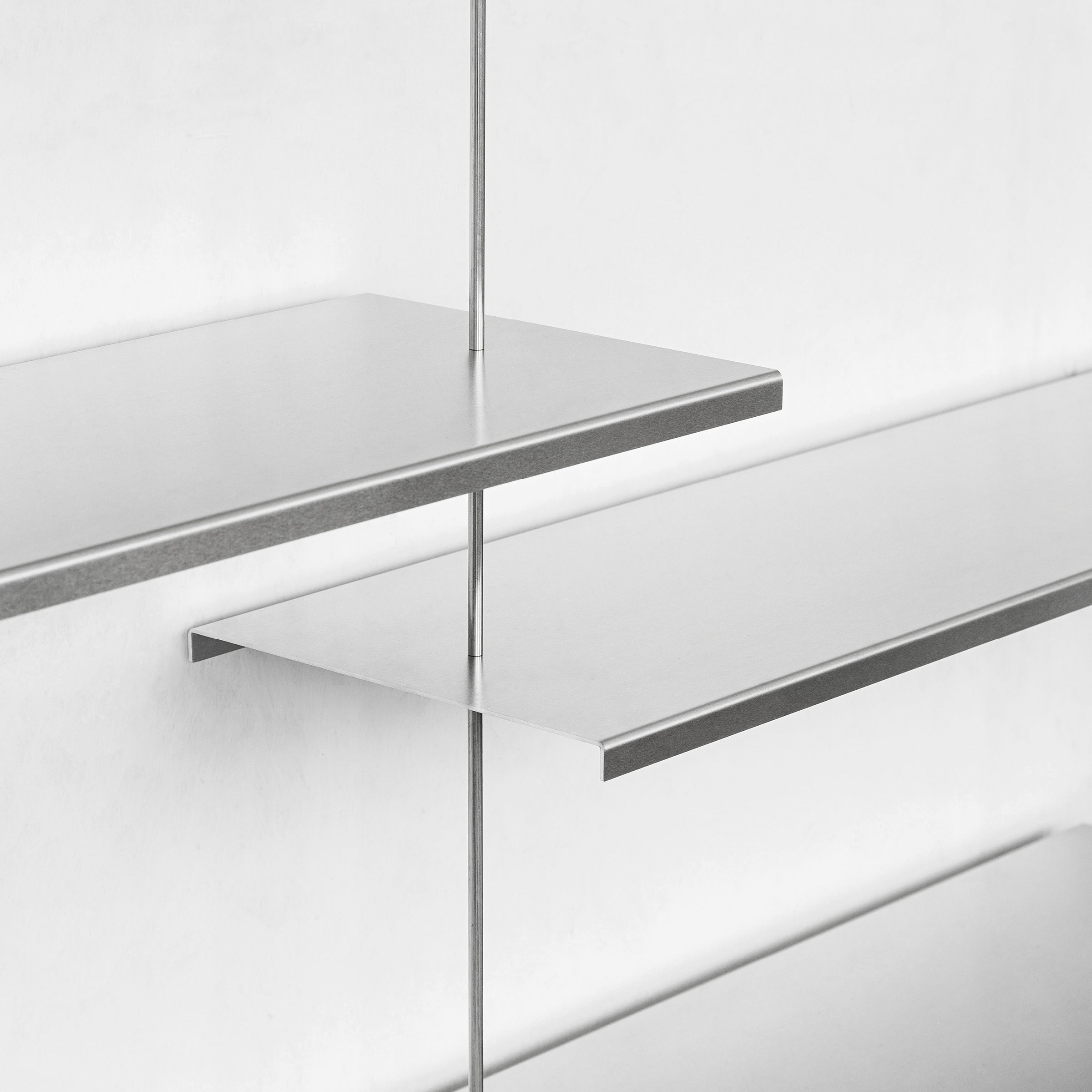 The Liesl shelves by Moormann feature a minimalist metal design with thin edges and vertical supports. Wall-mounted to add modern flair, their staggered arrangement creates an open, airy appearance on a white wall.