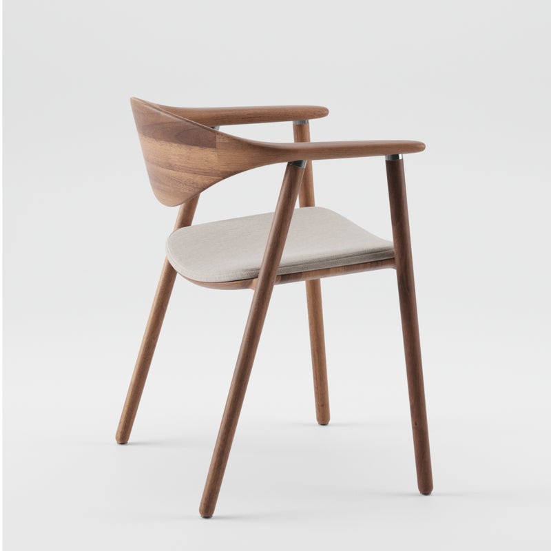 The Artisan NARU Chair features a minimalist design with a curved backrest and armrests, crafted from solid wood. It has four angled legs and a light gray cushioned seat, combining natural aesthetics with eco-friendly materials against a plain white backdrop.
